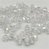 Clear faceted bicone crystal glass beads scattered on a white background for jewelry making