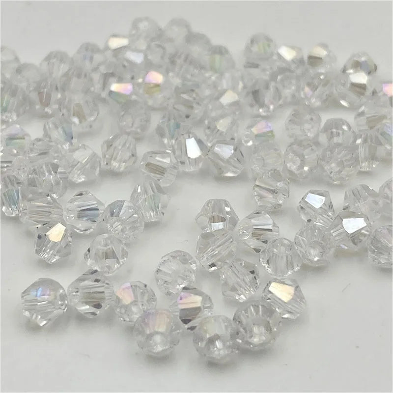 Clear faceted bicone crystal glass beads scattered on a white background for jewelry making