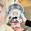 A fluffy white doll wearing a blue plaid bonnet and dress is held in a person's hand.