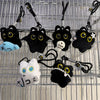 A collection of black plush cat keychain charms with yellow eyes and various accessories hanging from a metal grid.