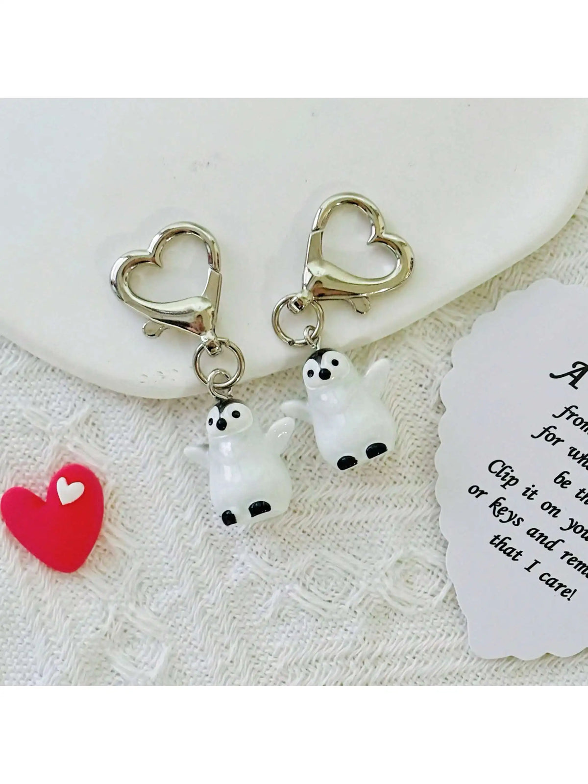 A set of silver heart-shaped keychains featuring cute white penguin charms.