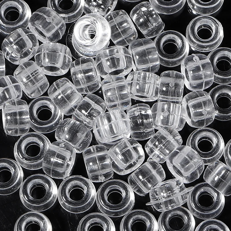 A close-up view of a pack of clear, round pony beads for jewelry making and craft projects.