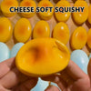 A hand holds a yellow cheese-shaped squishy stress relief toy surrounded by similar toys.