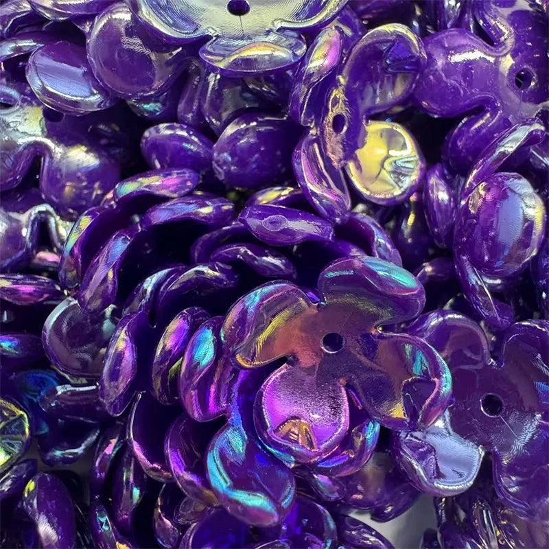 Close-up of deep purple acrylic beads shaped like four-petal flowers for jewelry making