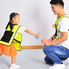 Two children are playing a game with a sticky dodgeball vest set indoors.