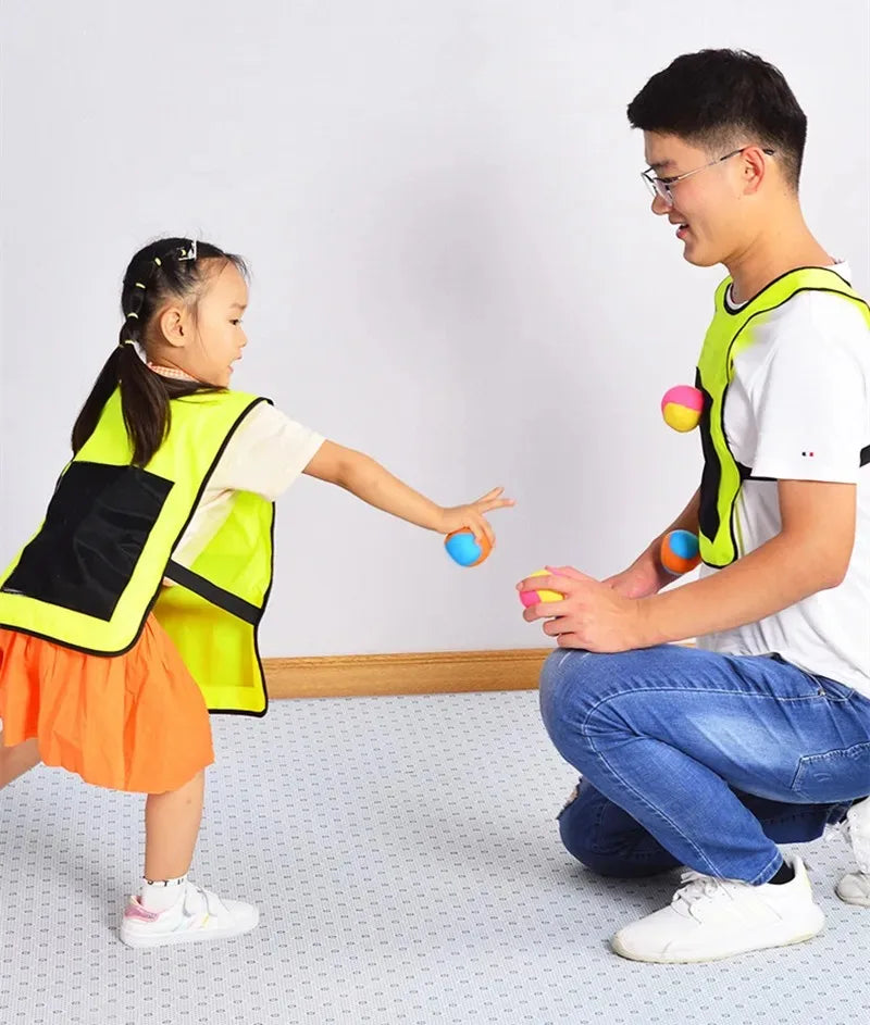 Two children are playing a game with a sticky dodgeball vest set indoors.