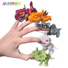 Une main tient plusieurs petits jouets de dinosaures colorés, dont un miniature violet, orange et gris.