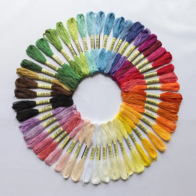 A circular arrangement of vibrant organic cotton embroidery floss in various shades of blue, green, purple, and yellow.