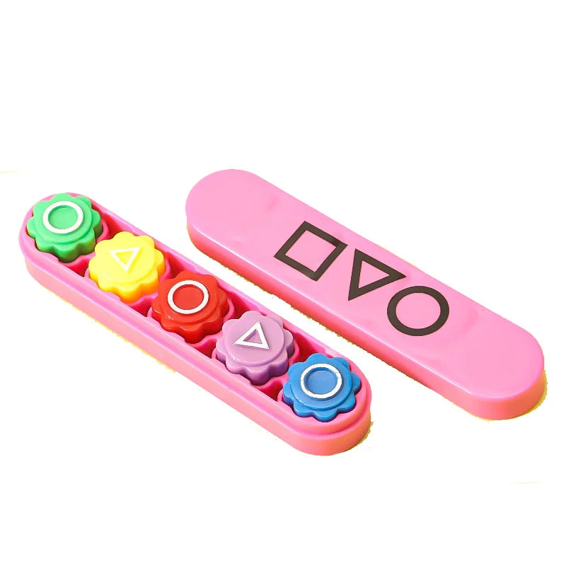 A pink plastic game set containing five colored pebbles used for a hand-eye coordination game.