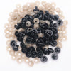 A pile of black plastic safety eyes and white washers for crafting projects