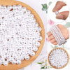 A pile of small, round ivory pearl beads arranged on a wooden board.