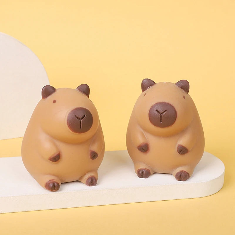 A pair of smooth, tan silicone toys shaped like capybaras used for squeeze stress relief.