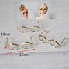 A set of five metal round glasses frames for dolls, including a pair and two models.