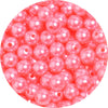 A close-up view of small, pink imitation pearl beads scattered in a pile.