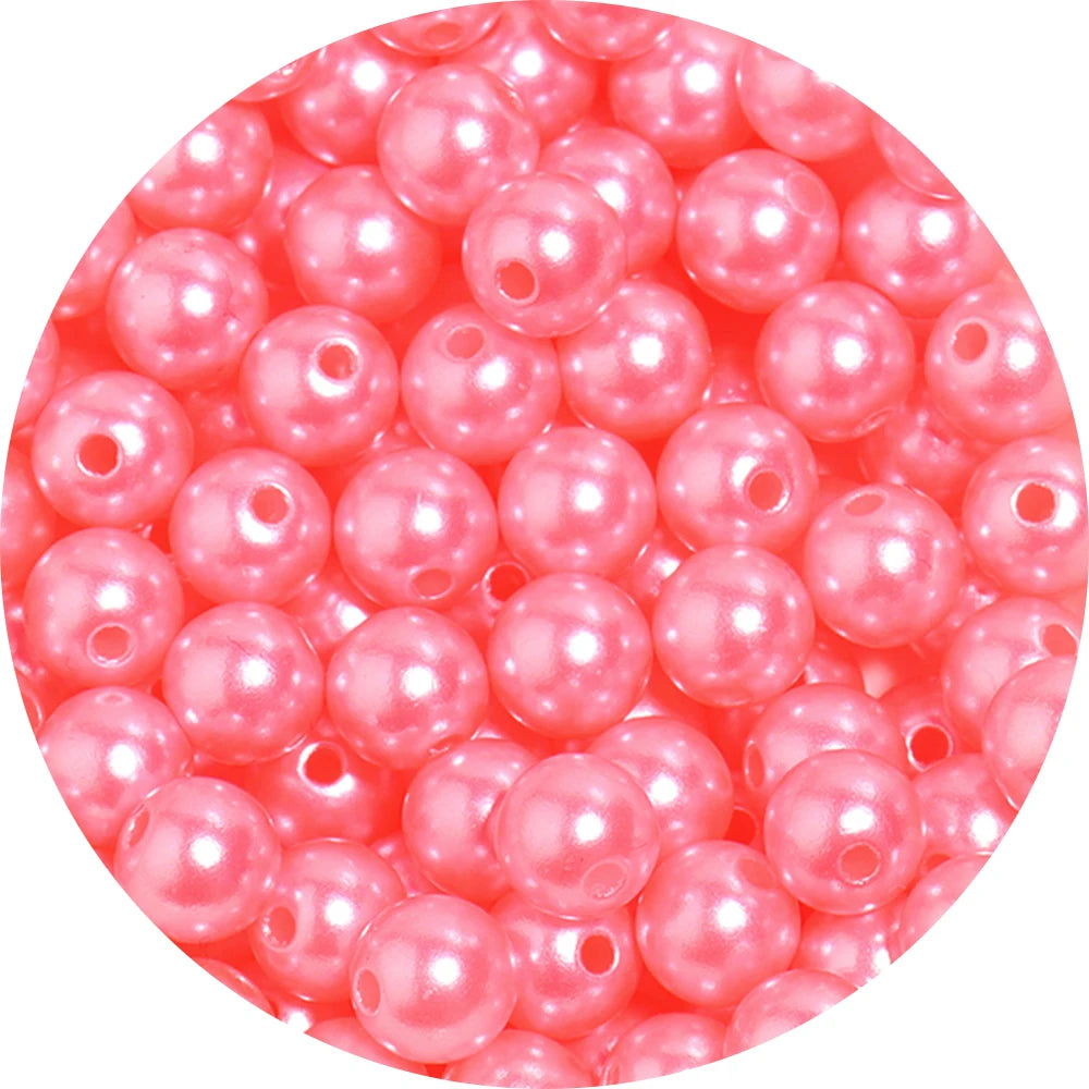 A close-up view of small, pink imitation pearl beads scattered in a pile.