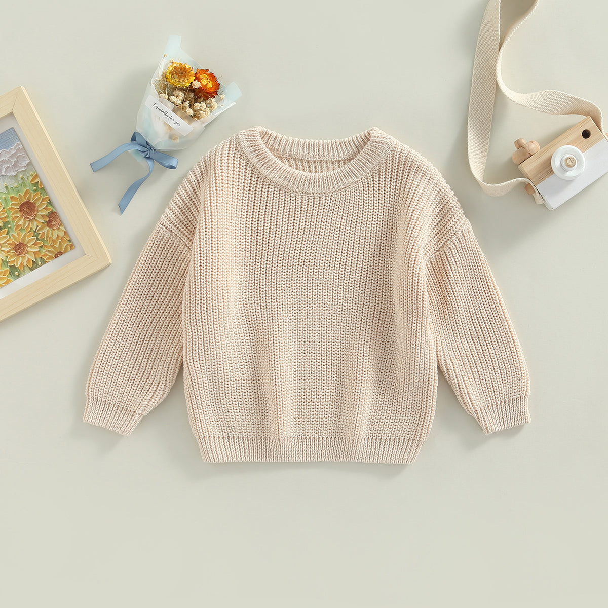 A beige knit pullover sweater for kids with long sleeves, displayed on a light background.