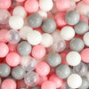 A close-up view of a bulk set of colorful plastic ocean ball pit toys in pink, white, and gray.