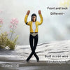 A male collectible plush doll dressed in a yellow jacket and black pants standing on a snowy surface.