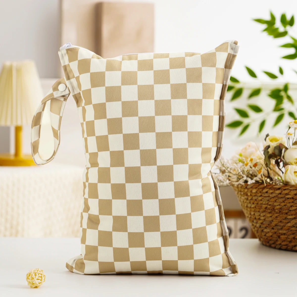 A beige and white checkered reusable zipper diaper cover and wet bag resting on a white surface.