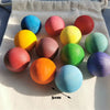 A collection of colorful, spherical sensory music trees with marble runs arranged on a white cloth.