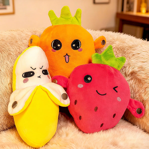 Three soft plush dolls shaped like an orange, a strawberry, and a lemon sitting on a fluffy surface.