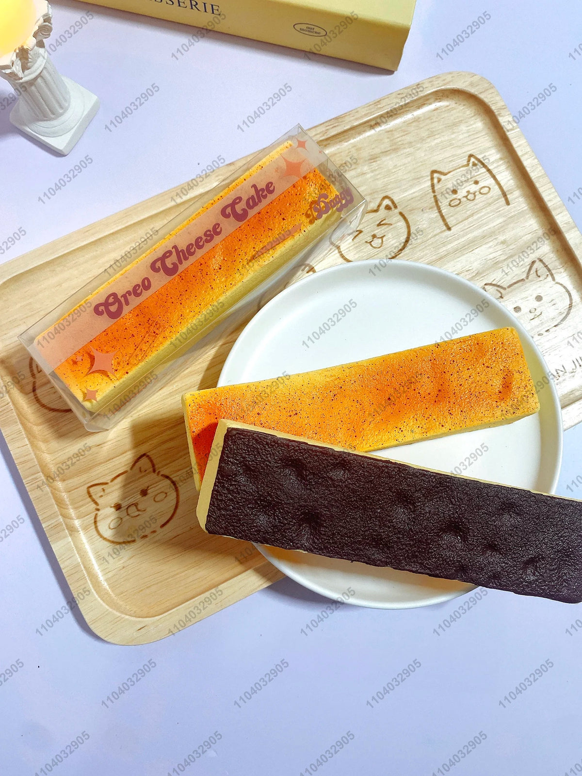 A slice of orange cheese cake and a dark chocolate butter stick squishy toy are displayed on a wooden cutting board.