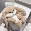 A light brown angry rabbit plush doll is displayed inside its packaging box.