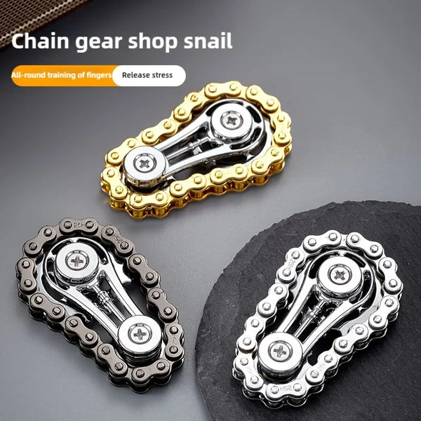 A set of metal chain gear snails or fidget spinners in gold and silver colors shown against a dark background.