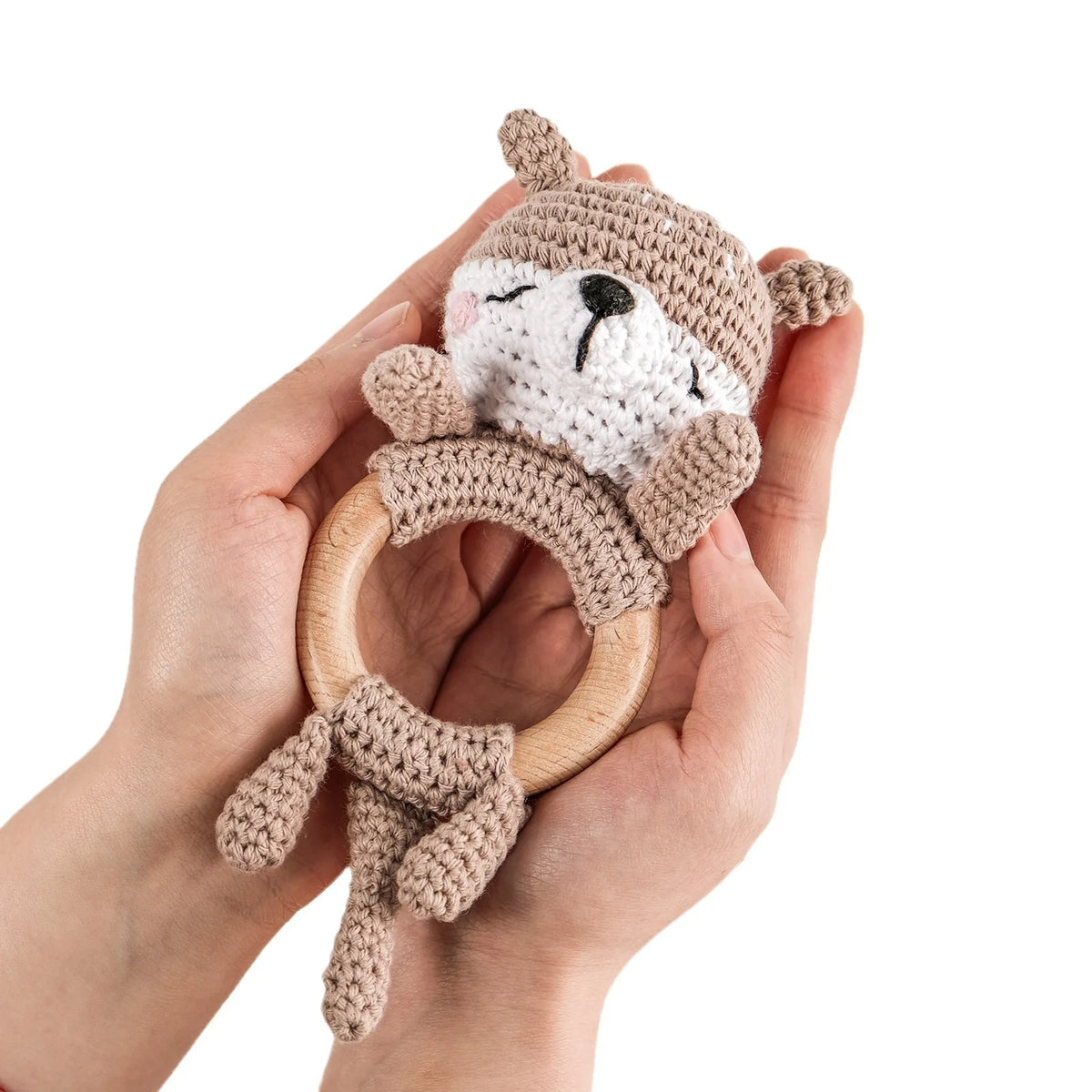 A hand holds a knitted brown bear rattle and teether ring made of wood