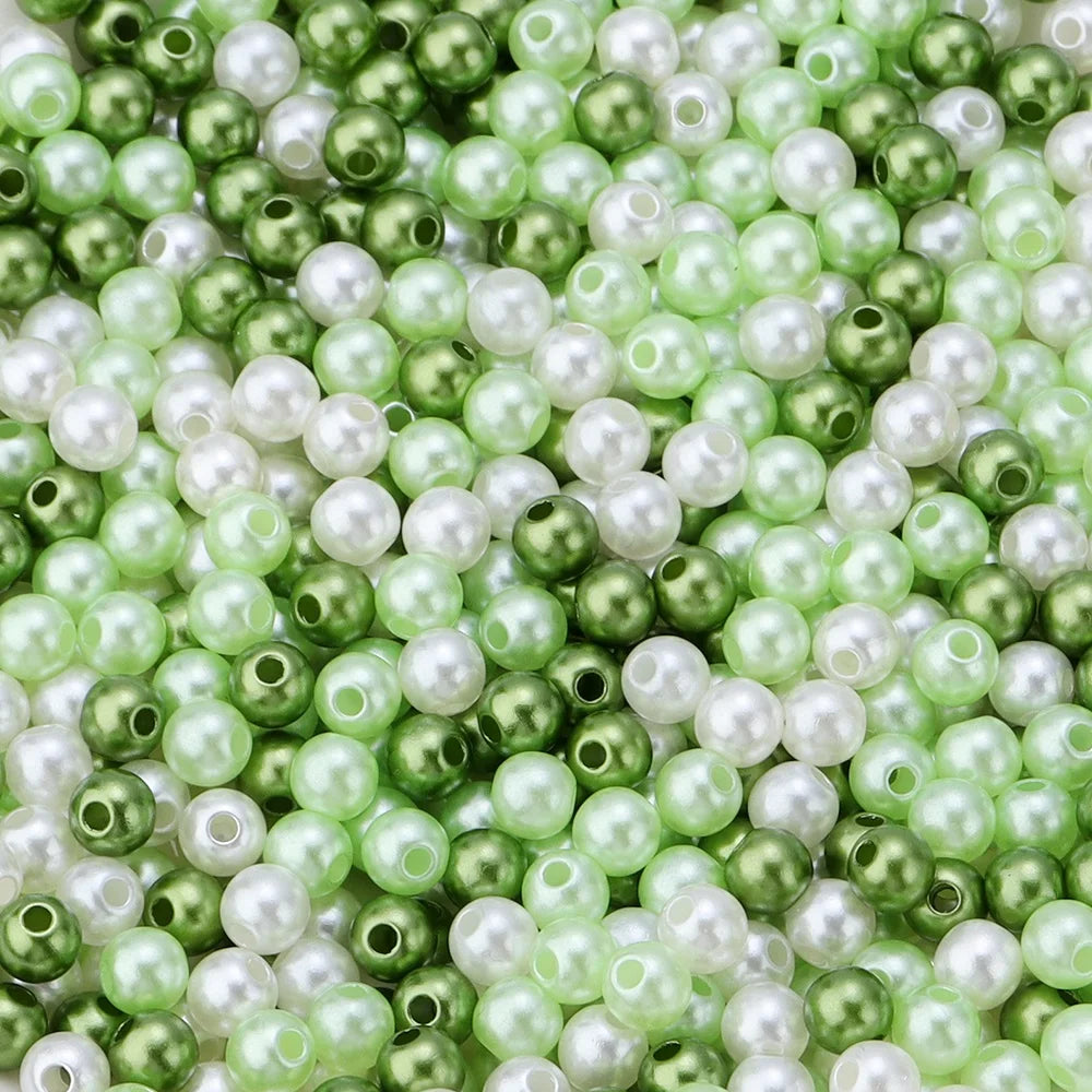A close-up of small, round imitation pearl beads in shades of green and white.