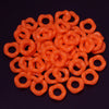A pile of bright orange acrylic doughnut spacer beads for jewelry making