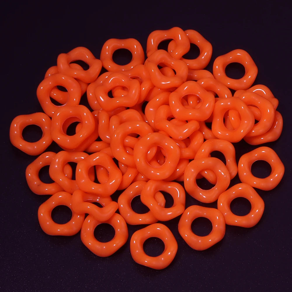 A pile of bright orange acrylic doughnut spacer beads for jewelry making