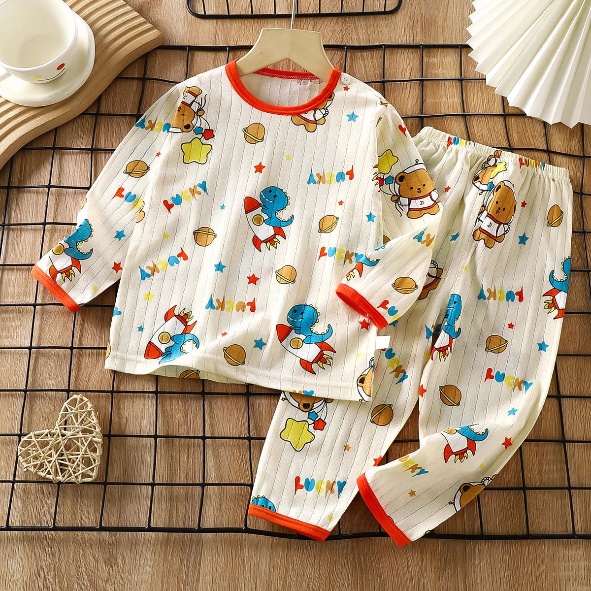 A white long sleeve cotton pajama set for children featuring colorful bears and stars on a grid background.