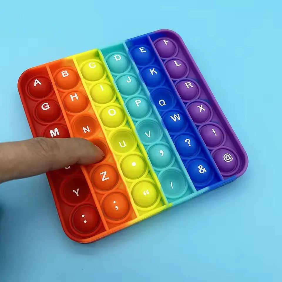 Une main pousse des tuiles en plastique colorées en forme de lettres et de chiffres dans un jouet anti-stress éducatif segmen