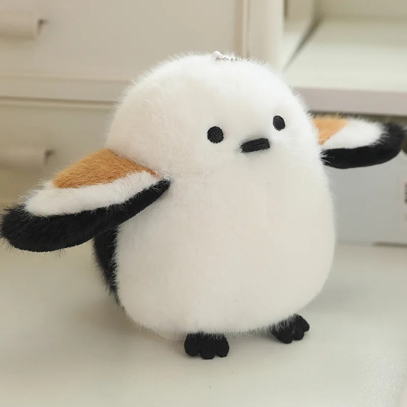 A white cartoon bird plush with black accents is shown against a light background.