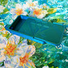 A teal diamond painting organizer tray with storage compartments placed on a colorful fabric background.
