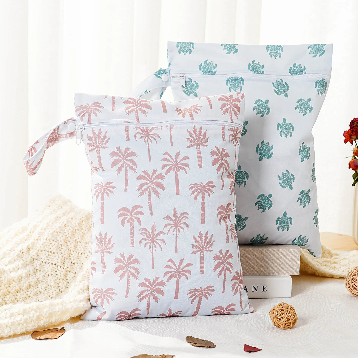 A set of two reusable waterproof baby wet bags featuring a light pink and green tropical leaf pattern.