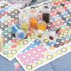 A collection of clear glass bottles filled with colored beads and labeled numbers arranged on a diamond painting grid.