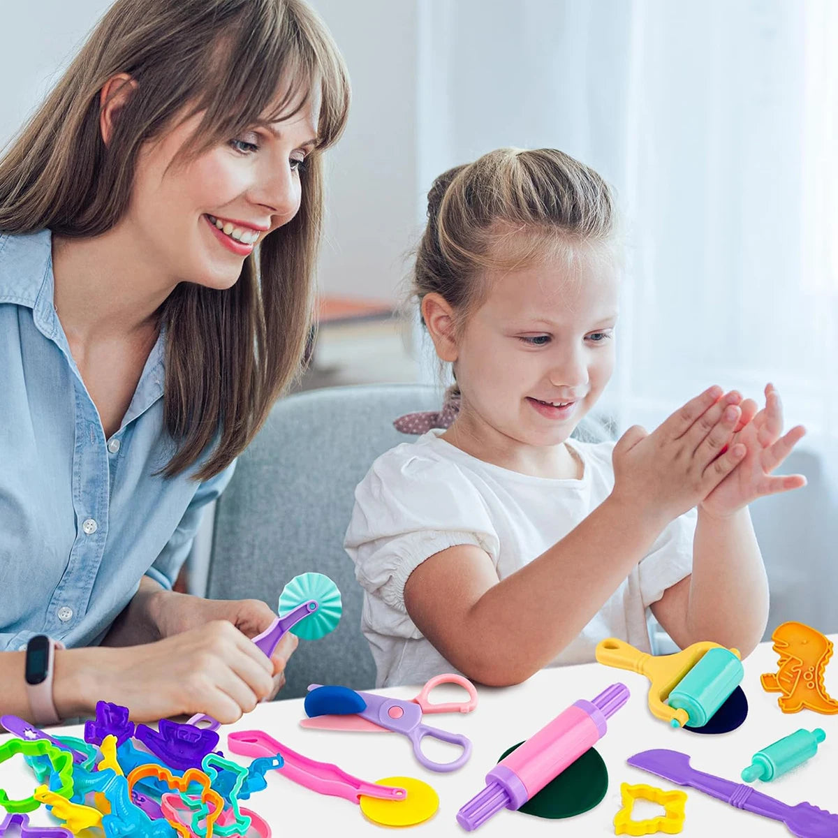 A child and an adult are using a complete dough tools kit for kids, including animal cutters, a rolling pin, and an extruder.
