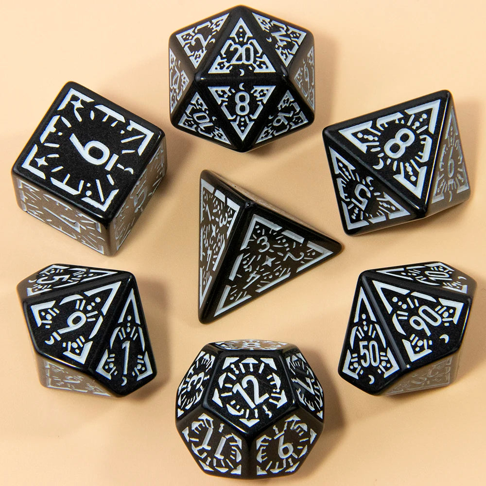 A set of seven fantasy carved polyhedral dice in black and white on a beige surface.