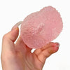 A hand holds a pink squishy ice ball mochi fidget toy for stress relief.