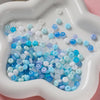 A collection of small, round glass spacer beads in various shades of blue and white are displayed in a white mold.
