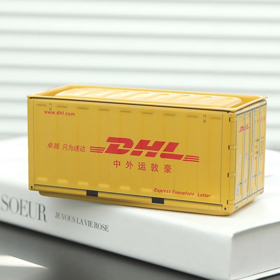 A yellow DHL shipping box is placed on a white book.