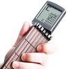 A hand holds a pocket guitar chord trainer with a wooden neck and a digital LCD display showing fret positions.