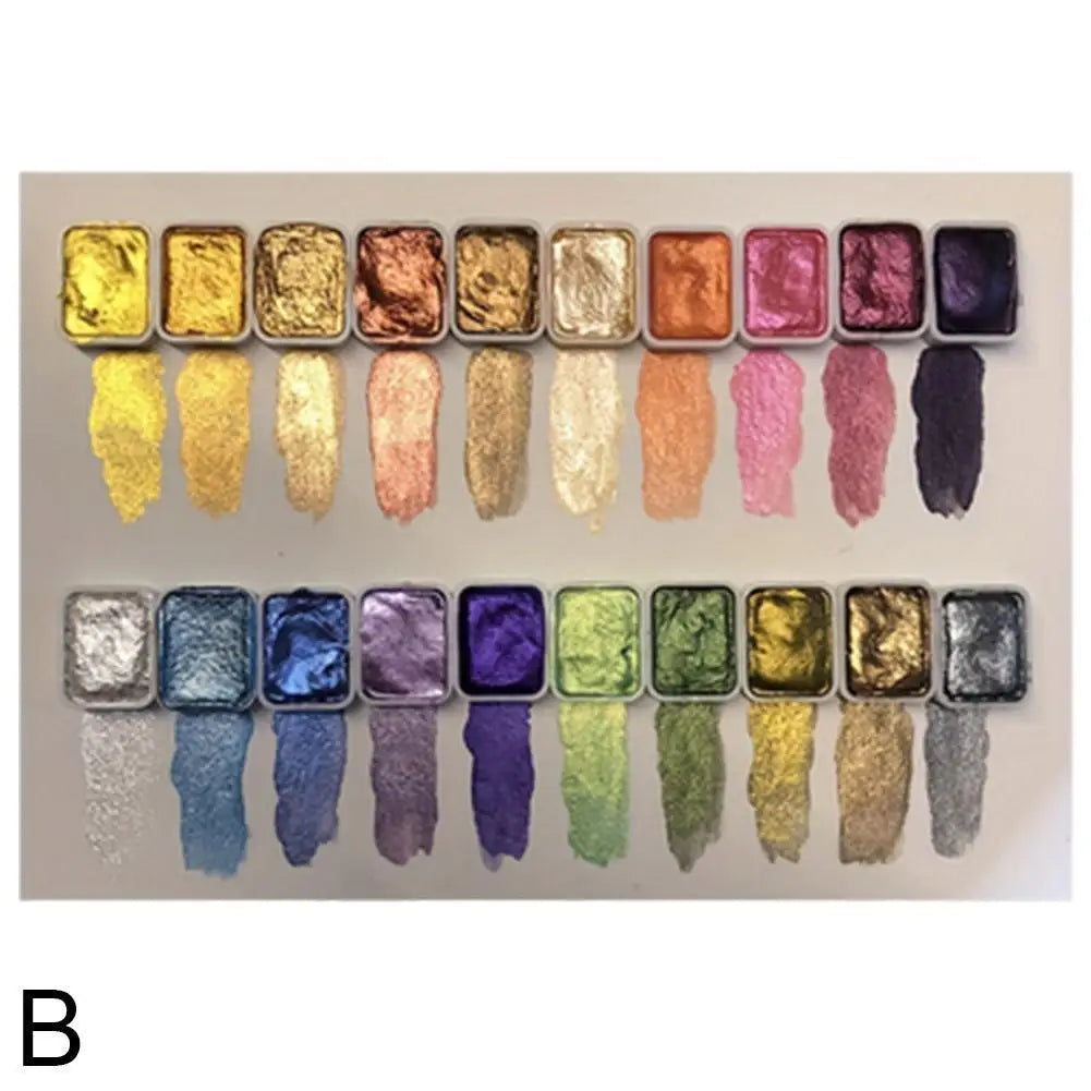A palette of 20 watercolor paints in various shades of gold, pink, purple, and green arranged in a row.