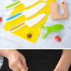 A set of white plastic play knives and a yellow cutting board are shown with fresh produce.