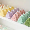 A display of various pastel silicone Christmas cookie and candle molds in shades of yellow, pink, purple, and green.