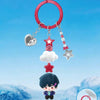 A mystery blind box figure of a character with dark hair and purple accents hangs from a red hoop with various charms.