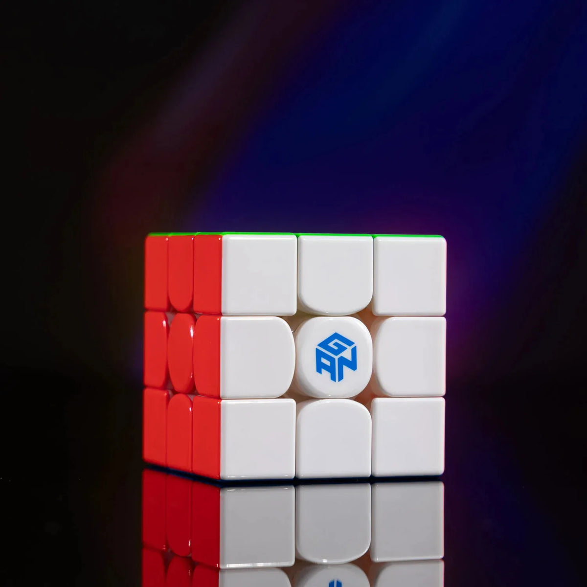 A red and white GAN 16 Maglev Max UV 3x3 magnetic speed cube resting on a reflective surface.