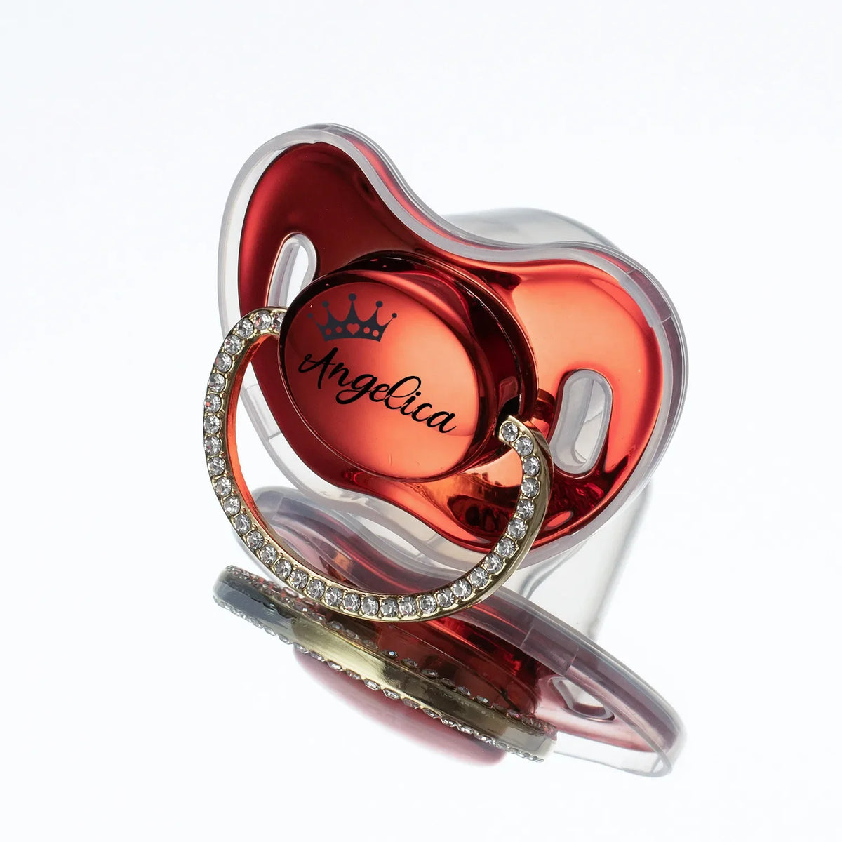 A personalized silicone baby pacifier featuring a pink heart shape and a rhinestone ring with the name Angelica engraved on i